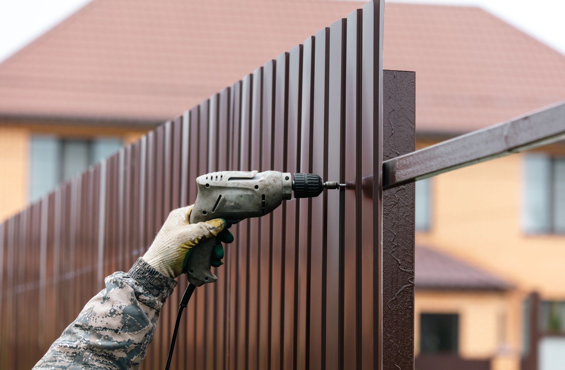 Workers install a metal profile fence